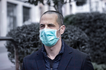 Ritratto di uomo con mascherina col giubotto in contesto urbano.
