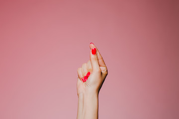 Woman's snapping hand with bright manicure isolated on pink background