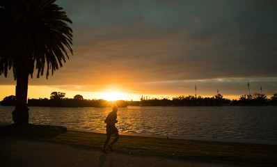 Man jogging by the lake at sunset