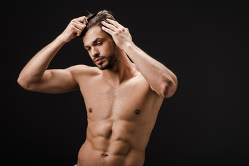 Fototapeta na wymiar bearded shirtless nude man combing hair isolated on black