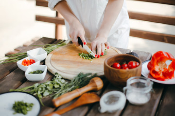Woman's hands chopping green onions on a wooden plate. Making guacamole