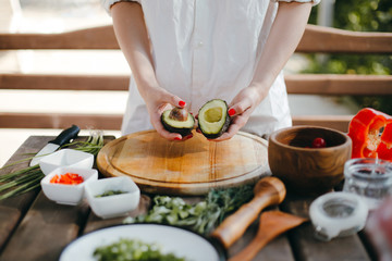 Woman's hands cutting avocado in half. Two avocado halves ready for guacamole making
