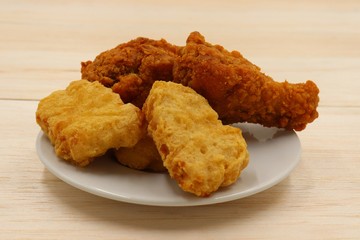 Nuggets and fried chicken on a white plate on wooden background