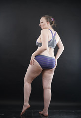 Obraz premium plus size woman shows her body in stretch marks and hair with cellulite and encourages you to love and accept yourself in any way . black background in the Studio. full- length photo.