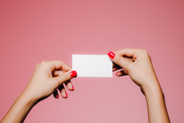 Woman's hands hold blank business card isolated on pink