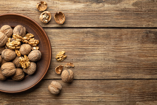 Nuts. Walnut kernels and whole walnuts on a table. Wooden background. Top view, flat lay with copy space.