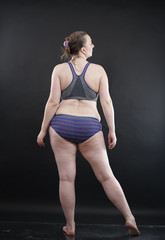 Obraz premium plus size woman shows her body in stretch marks and hair with cellulite and encourages you to love and accept yourself in any way . black background in the Studio. full- length photo.