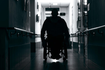 Silhouette of man on wheelchairs in corridor of hospital