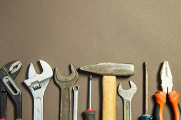 Construction tools on textured grunge paper consisting of pipe wrench, screwdriver, metal, hammer and free copy space on the top