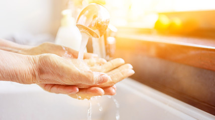 Seniorin beim Händewaschen mit Seife unter Wasser