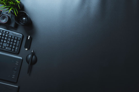 Top view of photographer or graphic designer with equipment on a black table with workspace or copy space.