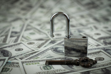Iron lock key on the group of money stack of 100 US dollars banknote a lot of the background