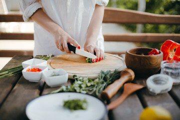Obraz na płótnie Canvas Woman's hands chopping green onions on a wooden plate. Making guacamole