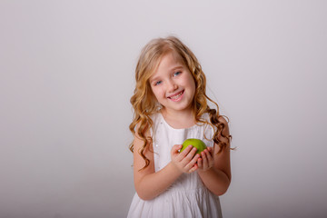 baby girl holding a green Apple smiling on a white background