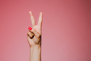 Woman's hands with bright manicure isolated on pink background peace gesture