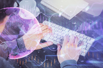 Double exposure of graph with man typing on computer in office on background. Concept of hard work.