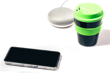 Digital Assistant concept. Smart speaker with smartphone and reusable coffee cup with green lid on...