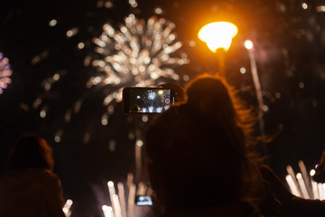 Fototapeta na wymiar young girl takes fireworks on the phone.