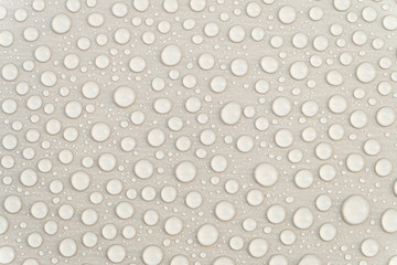 Fresh water drops on a gray glossy surface close-up. Waterproofing stain dye coating for construction. Abstract background.