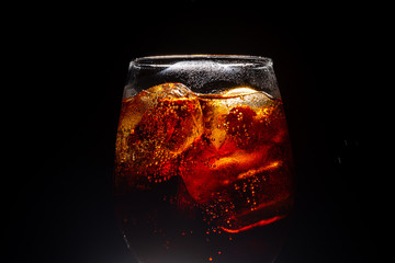 Soft drink glass with ice splash on dark background. Cola glass in celebration party concept