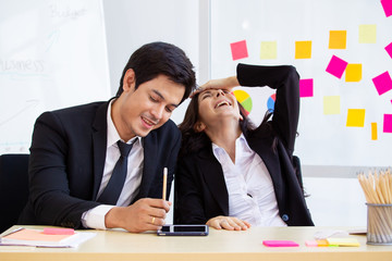 Asian and caucasian ethnicity partnership businesspeople discuss a business plan together by using touchscreen tablet in the meeting room in office. Co-worker colleague and teamwork concept.