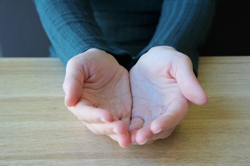 Empty hands folded together with palms up on light background