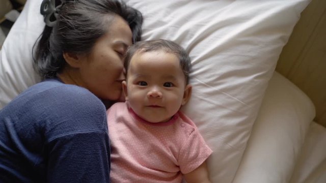 Asian little child lying in bed with their mother in the bedroom