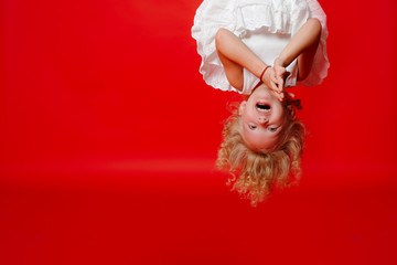 Funny child girl laughing with hands close to face isolated on red background