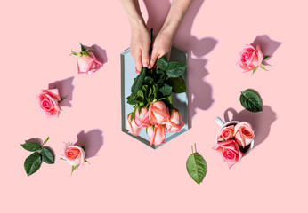 Fototapeta na wymiar Woman holding pink roses overhead view - flat lay