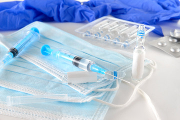 syringes with medicine, blue medical masks, medical gloves, vials of vaccine on a white , medicines