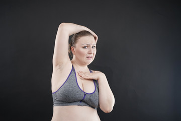 Fototapeta na wymiar unhappy woman shows her unshaved armpit. plus size middle age woman is not happy with hair in her armpits. Caucasian girl is emotional sad and upset. black background in the photo Studio.