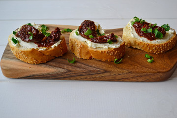 French baguette with cream cheese and dried tomatoes on a white background.