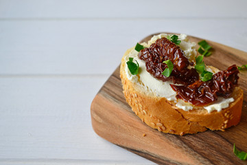 French baguette with cream cheese and dried tomatoes on a white background.
