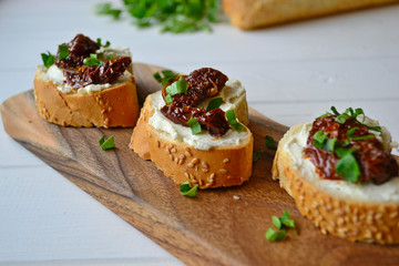 French baguette with cream cheese and dried tomatoes on a white background.