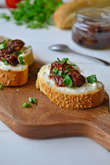French baguette with cream cheese and dried tomatoes on a white background.