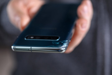 Man hold in hand modern smartphone with cracked corner