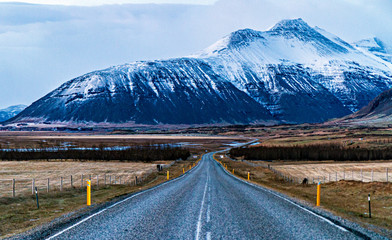 Fototapeta na wymiar Asfalto de una carretera hacia una mantaña en pleno invierno de Islandia