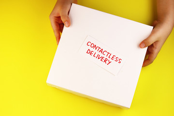 white box in hands and the text contactless delivery on a yellow background