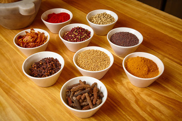 mixed spices in white bowls on wooden table