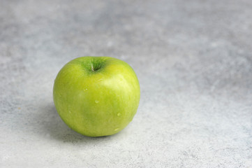 one green Apple on a gray background