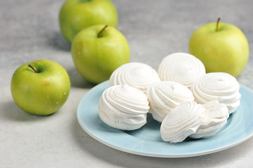 white marshmallows on a blue plate and green apples