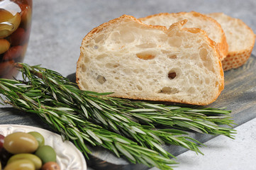 olives in a plate and ciabatta on a gray background