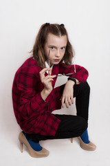 a fashionista teenage girl in a red plaid dress dressed mother's high-heeled shoes and glasses and indulges, pretending to be an adult.