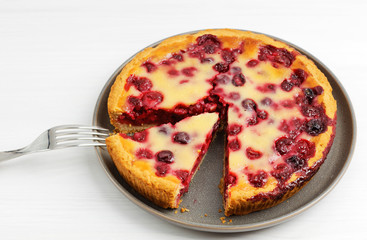 Closeup homemade berry pie with yogurt filling on white wooden table. Angle view. Shallow focus.