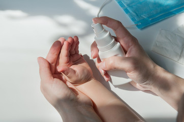 close-up of adult hands puffs on antiseptics on baby