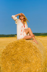 Naklejka na ściany i meble vertical portrait on a haystack of a pretty young woman with beautiful slim legs