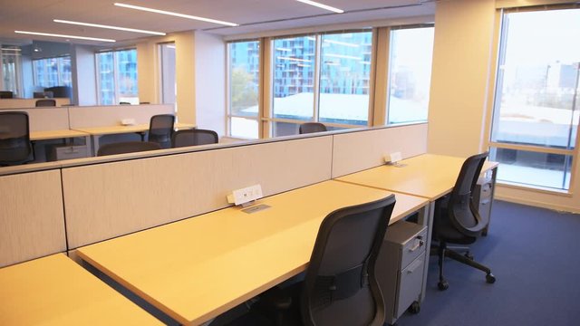 Empty modern office open space design with room, chairs and wooden tables and power outlet architecture and nobody by cubicle corporate desk, bright light from windows