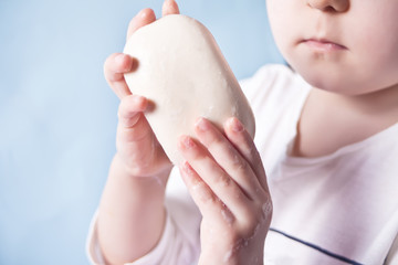 Child washing hands with a bar of white soap. Morning routine.