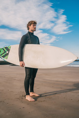 Surfer standing in the ocean with his surfboard.