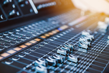 Close-up sound control dj sound console with blurry background with sun flare